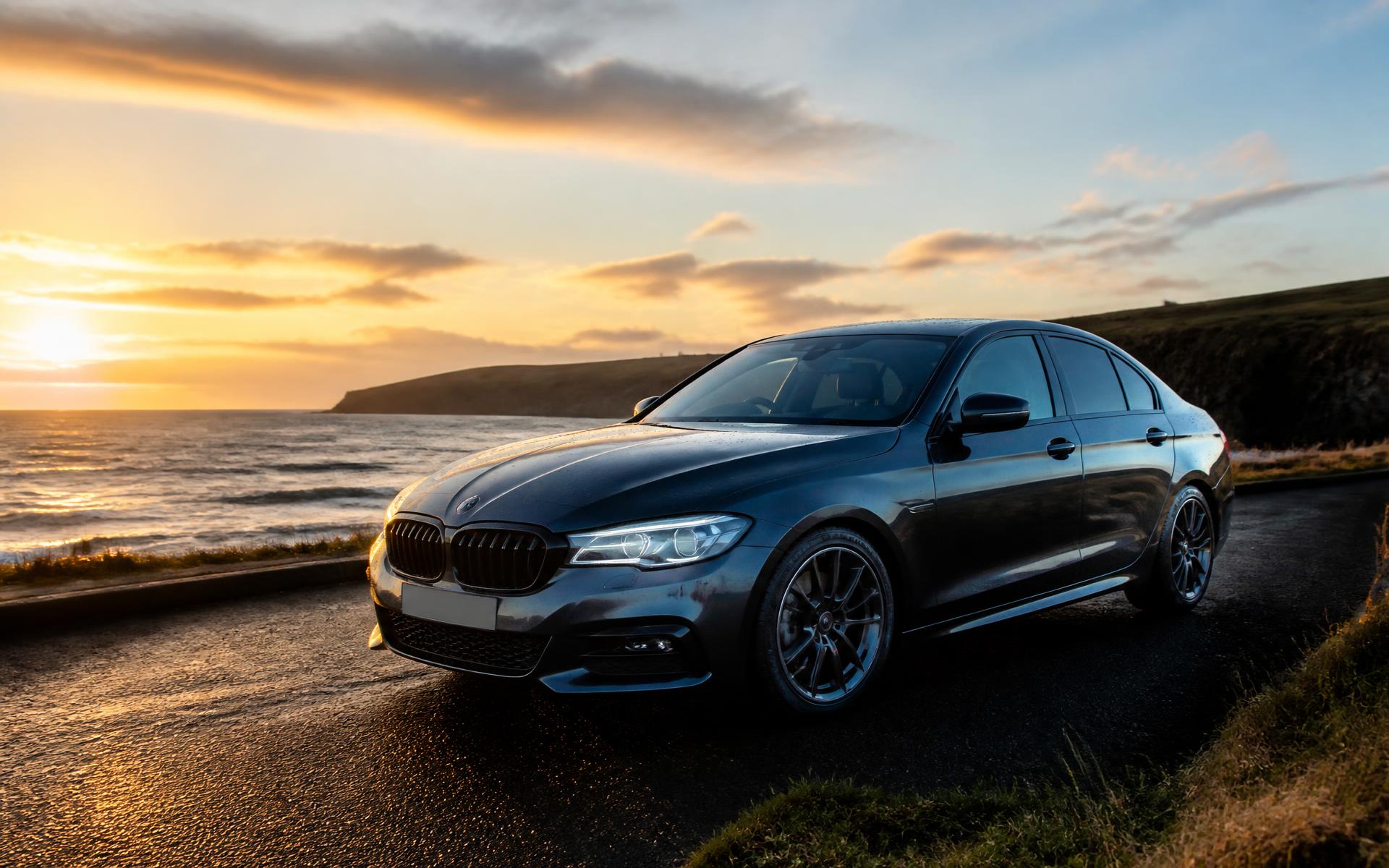 Freshly detailed dark saloon car on a coastal road at sunset in Co. Down